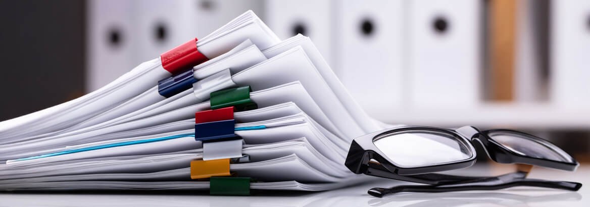 Eine Brille liegt vor einem Stapel Akten