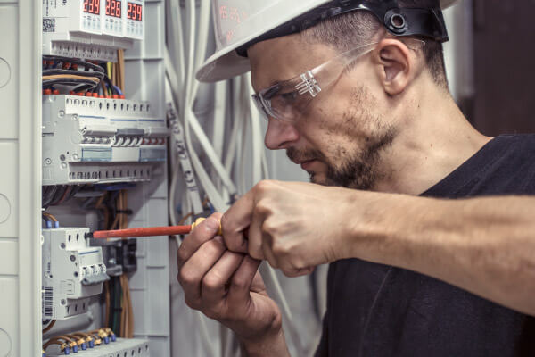 Bild eines Elektrotechnikers, der an einem Schaltschrank arbeitet