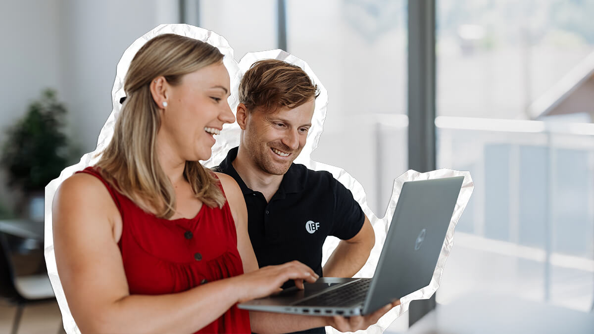 Mitarbeiter betrachten gemeinsam einen Laptop, einer zeigt dem anderen Inhalte