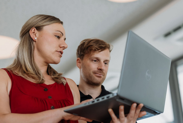 Zwei Mitarbeiter besprechen sich vor einem Laptop