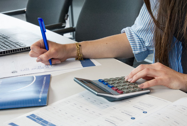 Hände eines Mitarbeiters bedienen einen Taschenrechner