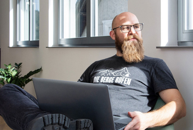 Ein Softwareentwickler sitzt auf einem Sessel mit einem Laptop im Schoß