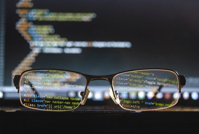 Brille liegt vor einem Monitor mit Code