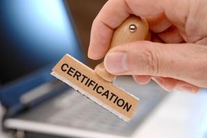 Bild auf dem eine Hand mit einem einem Stempel haltend zu sehen ist, auf dem Certification geschrieben steht.