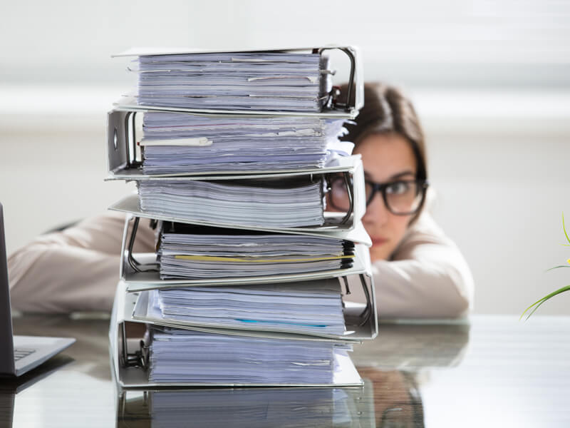 Aufnahme einer Mitarbeiterin hinter einem Ordnerstapel