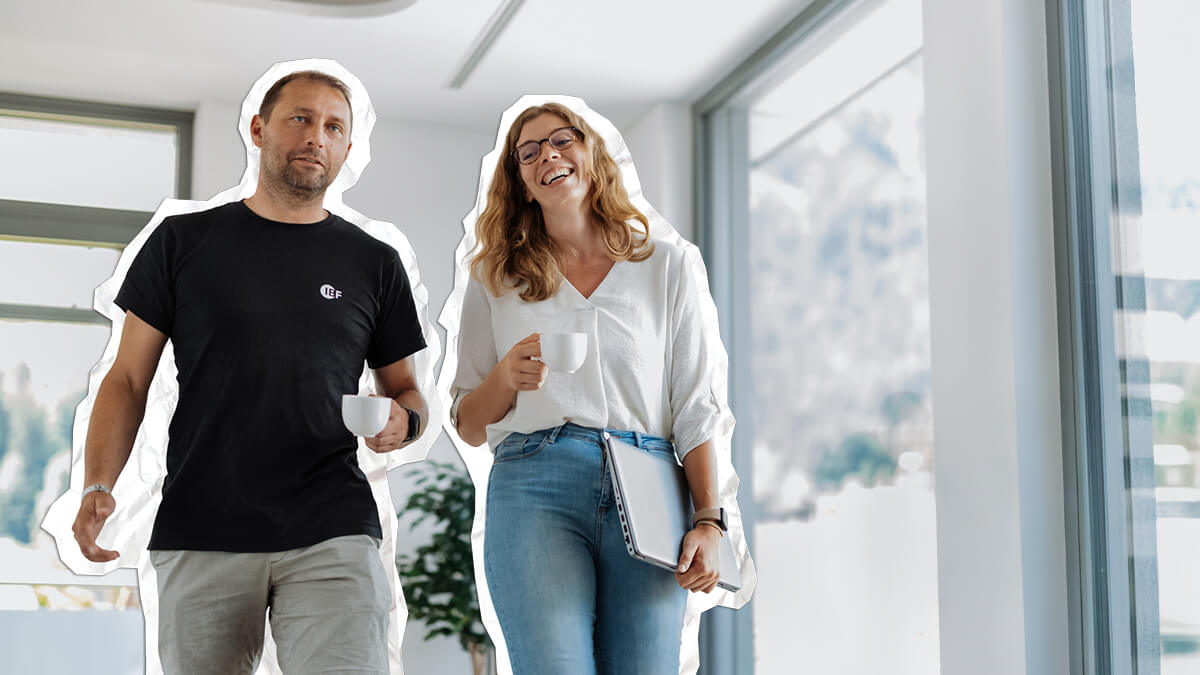 Zwei Mitarbeiter lächelnd mit einer Tasse Kaffee in den Händen