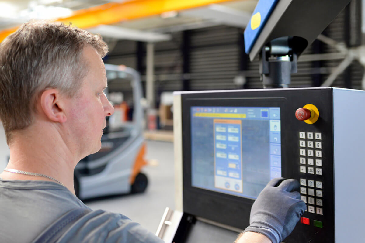 Bild von einer Person, die eine Maschine an einem Bedienpanel steuert