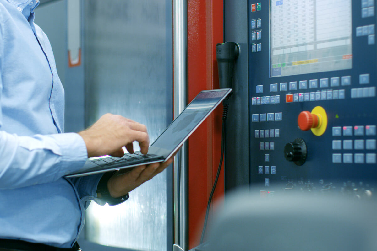 Bild eines Projektleiters, der am Laptop die Sicherheitsparameter einer Maschine überprüft